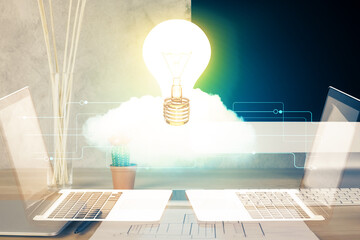 Computer on desktop in office with bulb icon hologram. Double exposure. Concept of idea.
