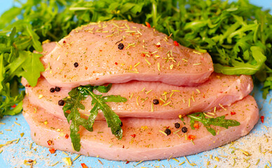 fresh turkey steaks with pepper and arugula on blue background