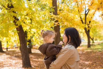 Fototapeta premium A young mother and little daughter are walking and laughing in the autumn park. Family. Autumn mood