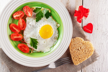 Fried egg with tomato slices, heart-shaped bread, gift box and red heart