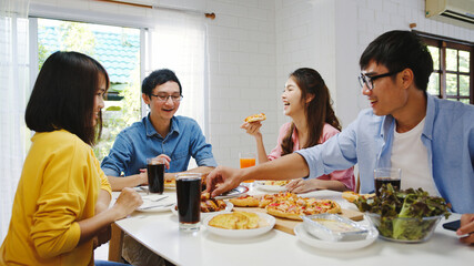 Happy young friends group having lunch at home. Asia family party eating pizza food and laughing...