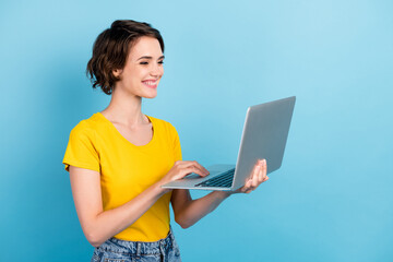 Profile photo of cute young girl hold netbook white smile wear yellow t-shirt isolated blue color...