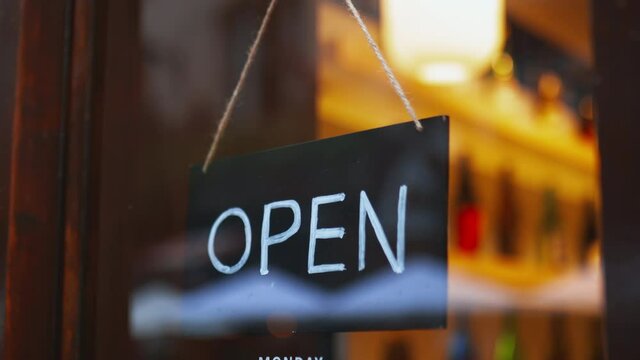 Close up view of an Open sign hanging on the glass door of a Japanese sake bar
