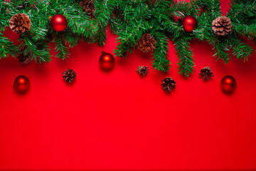 postcard with copyspace from a Christmas tree garland with cones, red balls isolated on a scarlet background.