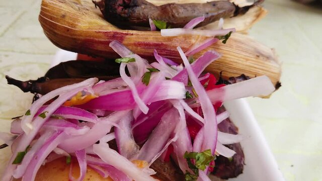 4k close up, steady shot of the famous Peruvian dish called Pachamanca. 3000 years old Inca barbeque style dish served in Huanuco, Peru. Onions, Potatoes, Meat and Beans. Cooked into an earth oven.