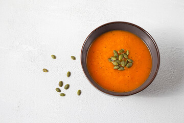 Roasted pumpkin soup with pumpkin seeds on white wooden background. Top view