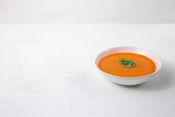 Roasted pumpkin soup with pumpkin seeds on white wooden background. Copy space