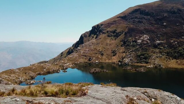 4k daytime video with a beautiful deep blue lake in the Peruvian Andes at the Lagoons of Pichgacocha in Ambo, Huanuco.Truck right to left with a wide angle shot. Clear blue sky and golden mountains