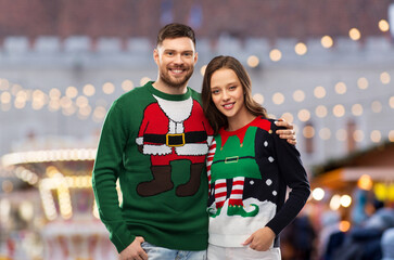 people and winter holidays concept - portrait of happy couple in sweaters over christmas market...