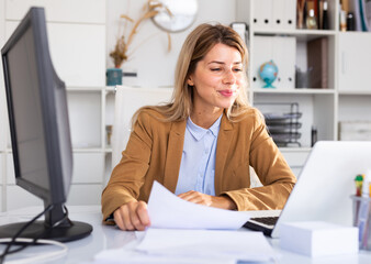 Woman working with papers and laptop in office