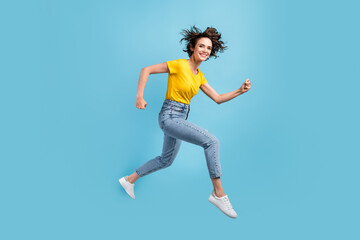 Fototapeta na wymiar Full length profile photo of girl jump rush run fists wear yellow t-shirt denim jeans footwear isolated blue color background