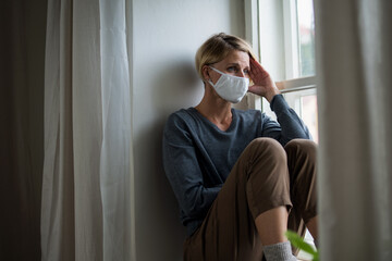 Woman indoors at home feeling stressed, mental health and coronavirus concept.