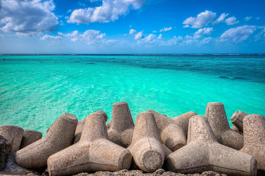 Sea wall defense concrete tetrapods contrast with the pristine waters and white sandy beaches of Shimojishima Island, Miyakojima, Okinawa, near the Shimojishima airport