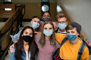 Front view of young students with face masks back at college or university, coronavirus concept.