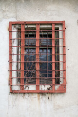 Obraz premium Grated window to an old abandoned warehouse. Rusty bars on the window