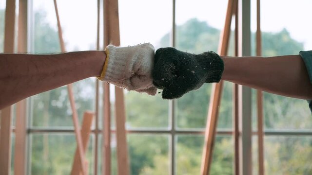 Fist bump collide of two carpenter, show strength teamwork with wooden background in the workshop. Slow Motion