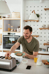 Handsome man preparing breakfast at home. Young man enjoying in morning.