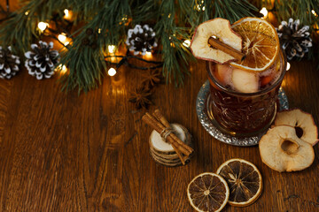 Sweet alcohol mulled wine with cinnamon and orange on wooden table with festive garland in cafe