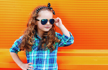 Portrait of little girl child wearing a checkered shirt, sunglasses over pink background