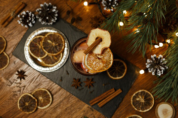 Hot delicious mulled wine as traditional Christmas drink arranged on table with dried orange and aromatic cinnamon sticks in cafe 