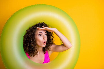 Photo portrait of shocked woman looking far ahead with hand at forehead through inflatable green...