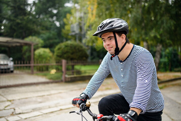Portrait of down syndrome adult man with bicycle cycling outdoors on street.