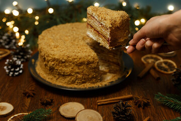 Woman taking piece of homemade honey cake placed on table at home for Christmas celebration 