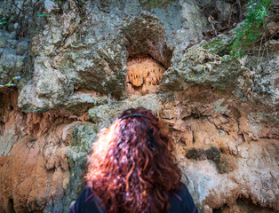 Unrecognizable ginger woman observes the stalactites over the rocks