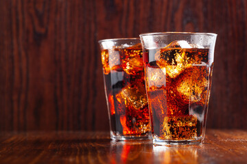 glass of cold cola soft drink with ice on wooden background