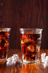 glass of cold cola soft drink with ice on wooden background