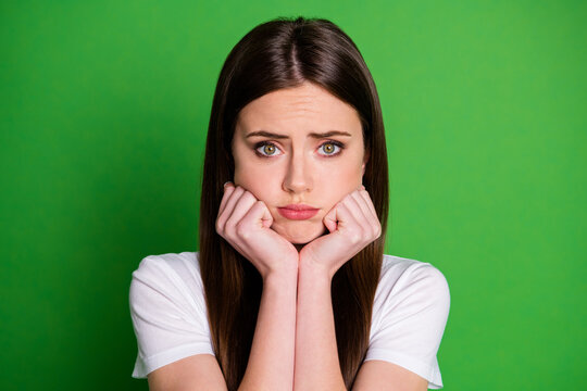 Photo portrait of sad girl touching cheeks with hands isolated on vivid green colored background