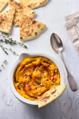 Delicious healthy homemade bean hummus with baked pumpkin, tahina and spices with flat bread on a light blue background, flat lay	