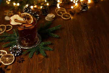 Traditional mulled wine with cinnamon and dry orange served on table with spruce branches and...
