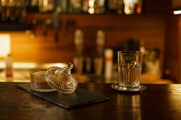 Empty glass for cappuccino and bowl with brown sugar placed on wooden counter in cozy bar 