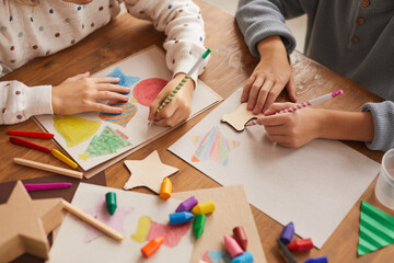 High angle close up of children tracing shapes while drawing Christmas cards in school, copy space