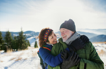 Portrait of senior couple hikers standing in snow-covered winter nature.