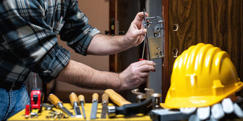 Carpenter at work repairs and installs the door lock. Carpentry.