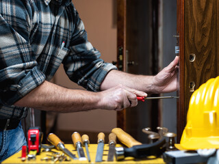 Carpenter at work repairs and installs the door lock. Carpentry.