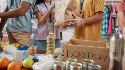Cropped shot of male and female volunteers packing food donation for needy people, Young team...