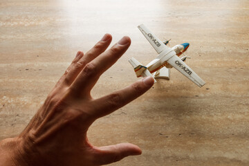 Scale model  of a two-engined passenger plane and a male hand that wants to take it. Toy. 