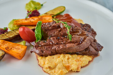 Grilled steak on mashed potatoes with grilled vegetables.