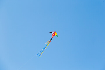 Fototapeta na wymiar kite on the blue sky in sunny weather and wind. Kite flying in summer with copy space. Liberty.