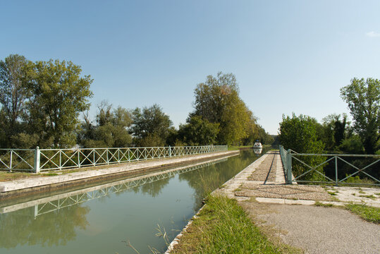 Un bateau de plaisance s'approche de ce pont canal qui lui permettra de passer sans encombre la rivière située en dessous sur le Canal Latéral à la Garonne