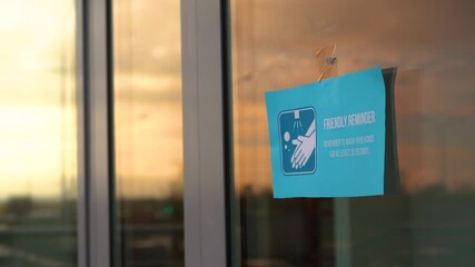 Cafe owner hangs "Friendly reminder - remember to wash your hands at least 20 seconds" sign on glass door during pandemic covid-19 coronavirus quarantine. Keep yourself and others safety.