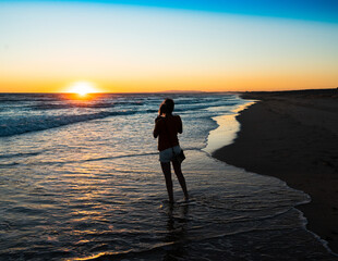 Chica hace fotos del atardecer en una bonita playa al sur de Portugal