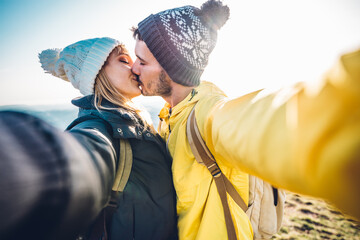 Hikers taking a selfie on the top of the mountain - Couple in love kissing outdoor - Bright filter