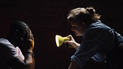 Side view of woman police officer psychologically abusing suspect man while interrogating