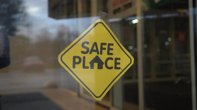 Restaurant owner hangs "Safe place" sign on glass door during pandemic covid-19 coronavirus quarantine. Business is opening after lockdown.