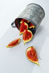 Bright red ripe figs in a metal mug on a white background.
