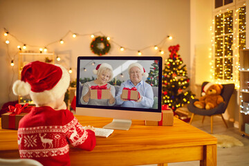 Little boy video calling grandparents who have prepared Christmas presents for him